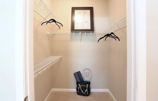 A small closet with a bag and a racket on the floor.