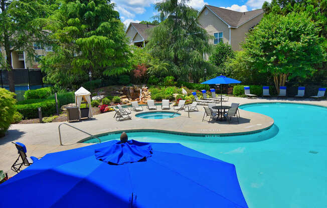 A blue umbrella is in the foreground of a swimming pool.