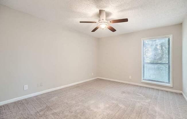 A room with a ceiling fan and a window with blinds.