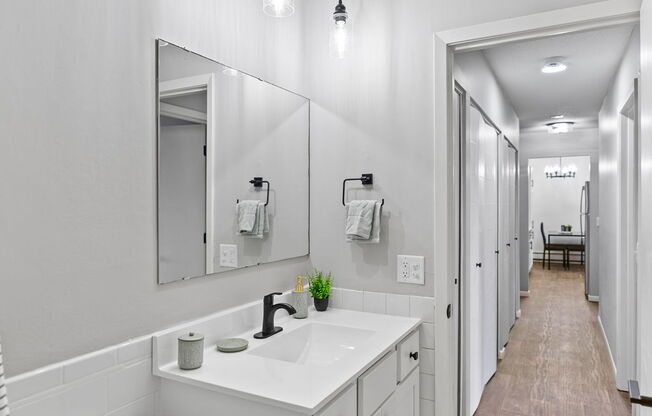 a long white bathroom with a toilet sink and mirror
