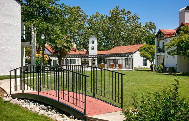 Apartment Exterior With Lush Grass, Paved Walkways With Trees and Bushes, and a Small Decorative Bridge at Laurel Creek, Fairfield, CA