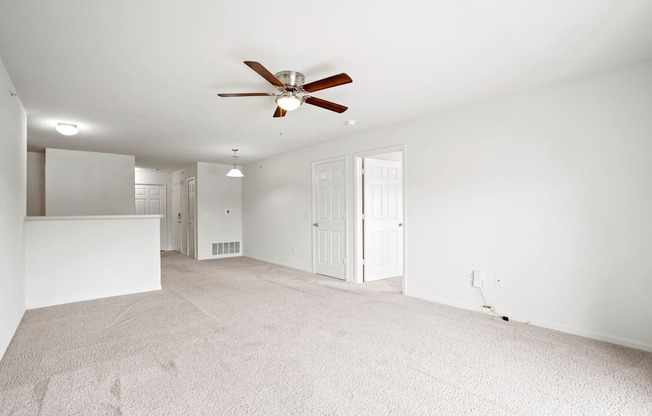 A room with a ceiling fan and carpeted floor.
