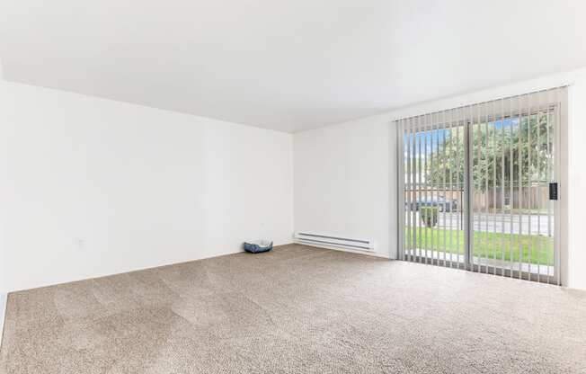 an empty living room with a large window and carpeting