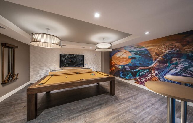 a game room with a pool table and a mural on the wall