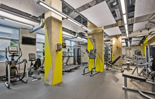 a gym with weights and other exercise equipment in a building with windows