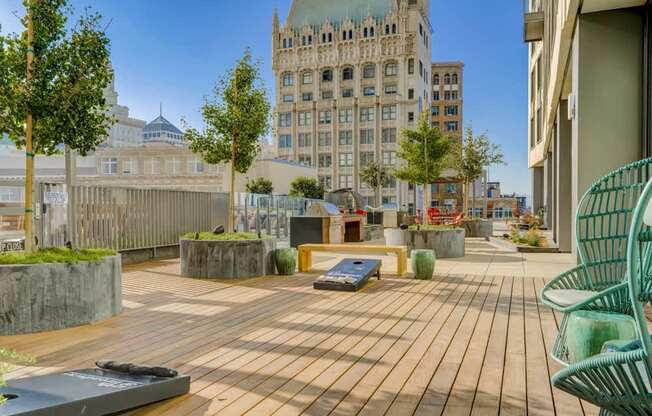 A wooden deck with a green chair and a bench in the foreground with a building in the background.