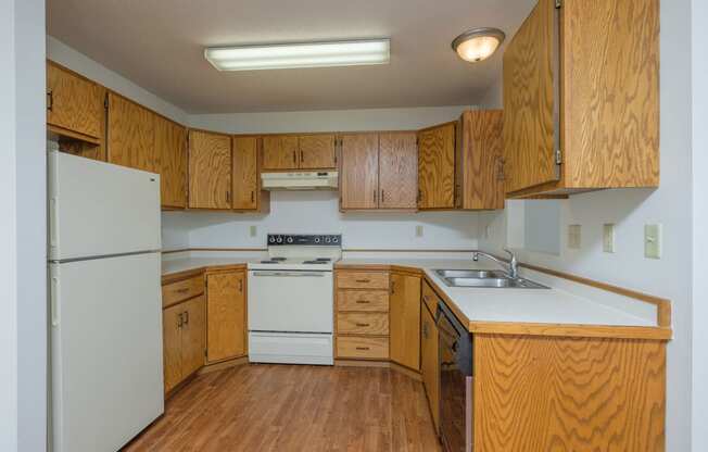 a kitchen with white appliances and wooden cabinets. Fargo, ND Park Circle Apartments.