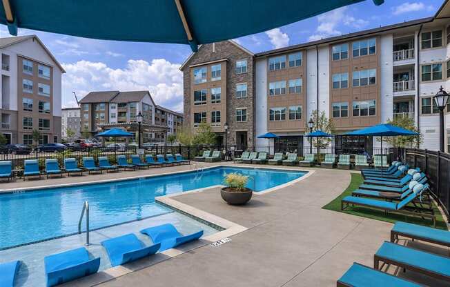 A large swimming pool surrounded by blue lounge chairs and umbrellas.
