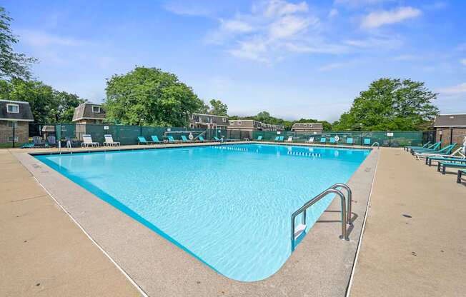 A large outdoor swimming pool with a blue tiled edge and a metal handrail.