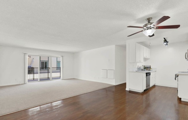 an empty living room with a ceiling fan and a kitchen at Camino de Oro Apartments, Torrance, California