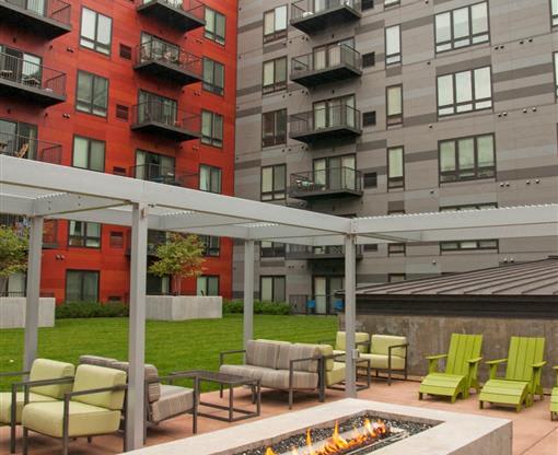 A patio with a fire pit and chairs.