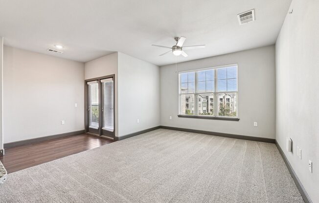 A room with a carpeted floor and a ceiling fan.