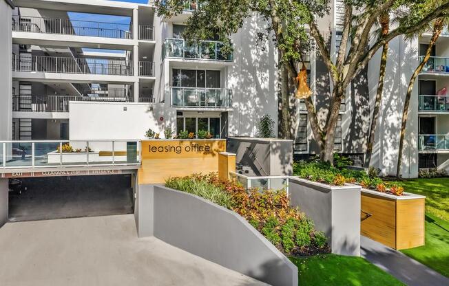 A leasing office is located in a courtyard surrounded by trees and plants.