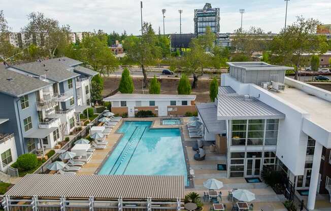 A large swimming pool is surrounded by a metal fence and several lounge chairs.