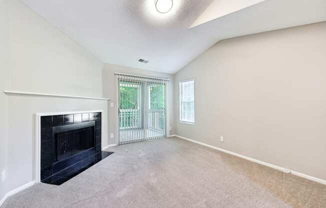 an empty living room with a fireplace and a balcony