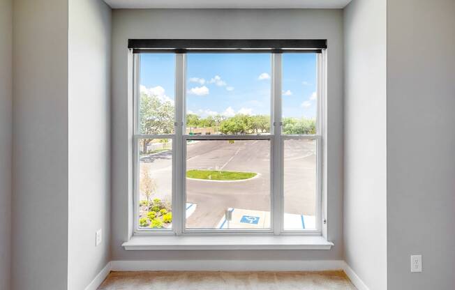 an empty room with a large window and a view of a parking lot