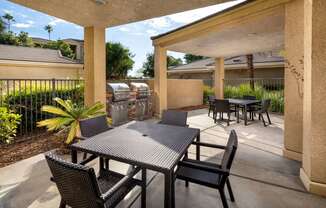 a patio with a table and chairs and a grill