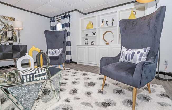 Two grey chairs and a glass coffee table in our resident lounge in the leasing office at Maplewood apartments in Shreveport, LA.
