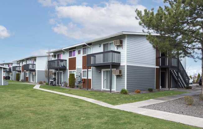 a row of town homes with a lawn and trees in front of them