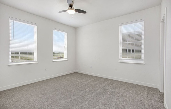 A bedroom with a ceiling fan and three windows at Meadowbrooke Apartment Homes in Kentwood, MI 49512