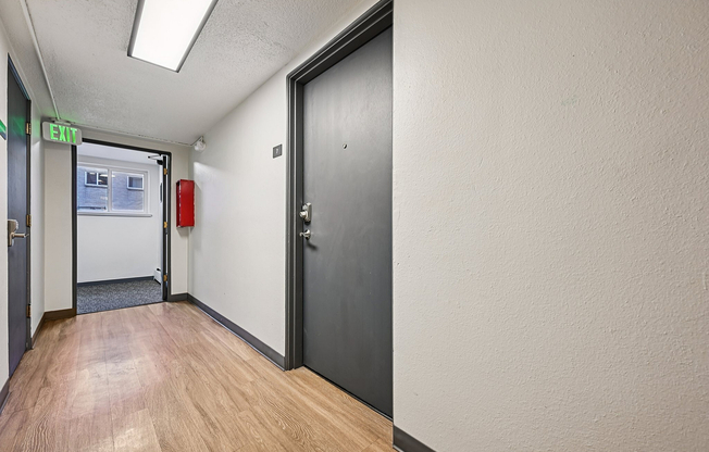 Bright and inviting apartment hallway featuring sleek hardwood floors, modern lighting, and a secure entry door.