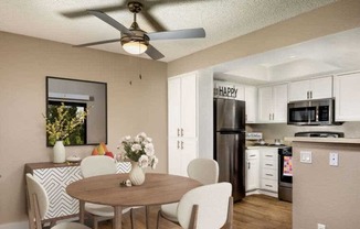 A dining room with a table and chairs and a kitchen in the background.
