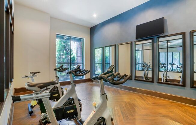 A room with a wooden floor and a wall with a mirror and a television.
