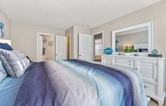 A bedroom with a bed covered in a blue and grey striped comforter.