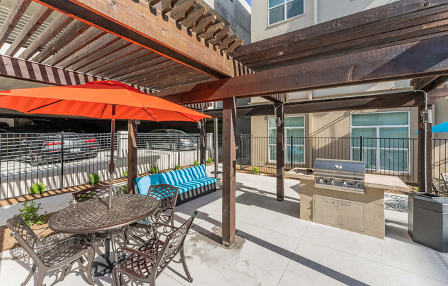 a patio with a table and chairs and a grill at Residences at 3000 Bardin Road, Grand Prairie, TX
