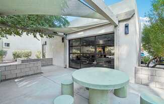 A white table and two stools are in front of a glass door.