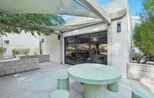 A white table and two stools are in front of a glass door.