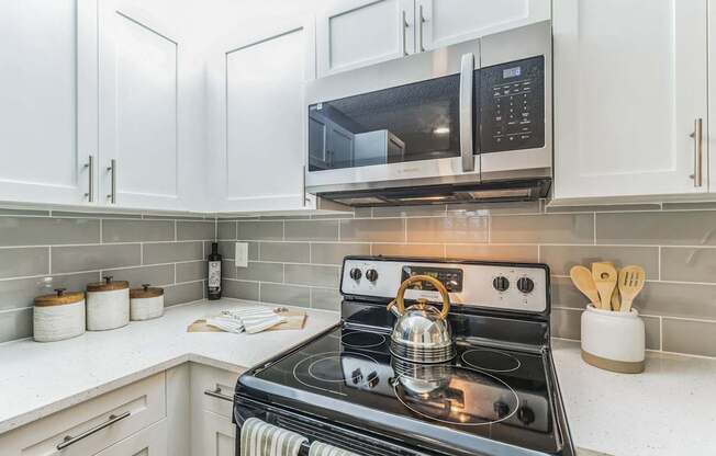 Kitchen with white cabinets and a stove and a microwave