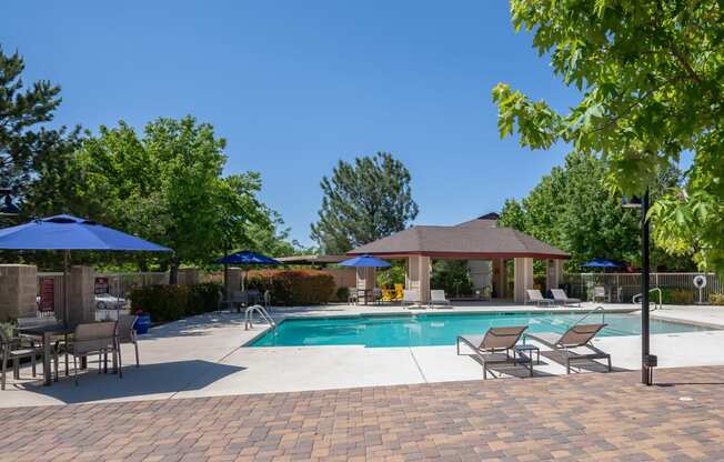 a swimming pool with patio furniture and umbrellas