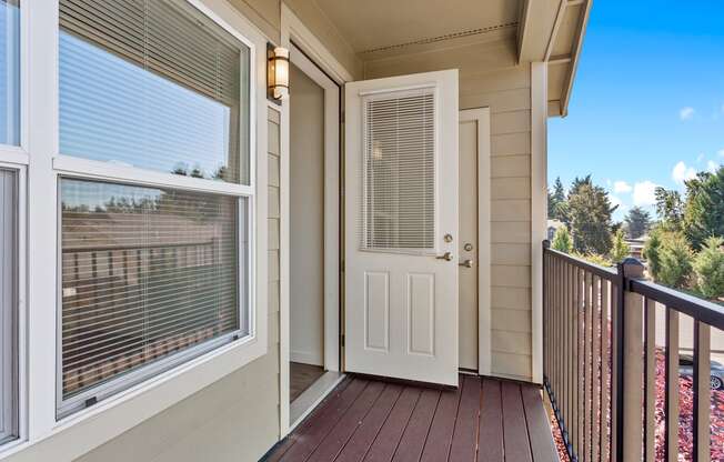 A white door is open to a deck with a railing.