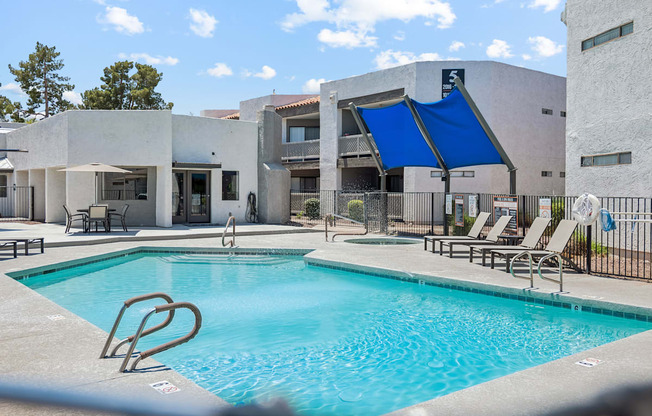 A swimming pool in front of a building with a blue tarp covering a part of it.