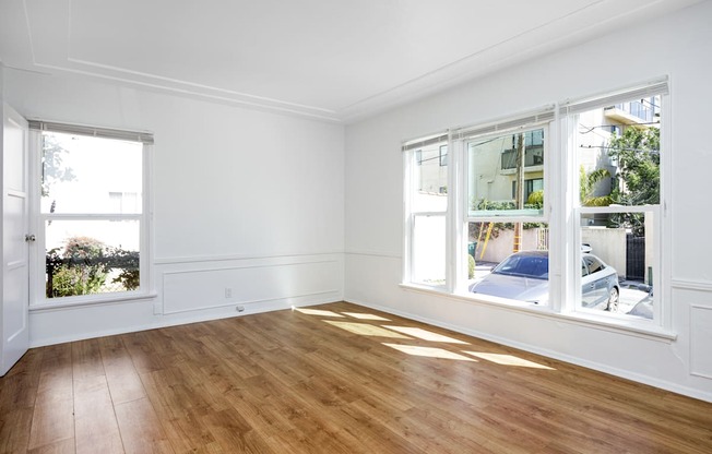 an empty living room with white walls and a wood floor