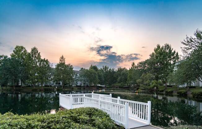 a white bridge over a lake with a sunset in the background