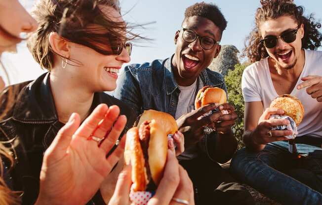 a group of people eating hot dogs    and laughing