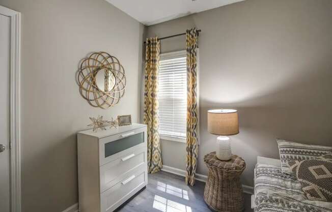 a bedroom with a bed and a dresser in front of a window