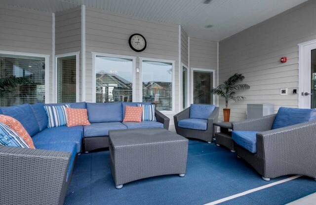 Sitting area outside of clubhouse with 1 L-couch and 2 chairs