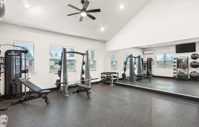 A spacious gym with a variety of equipment including treadmills, weights, and a bench press.