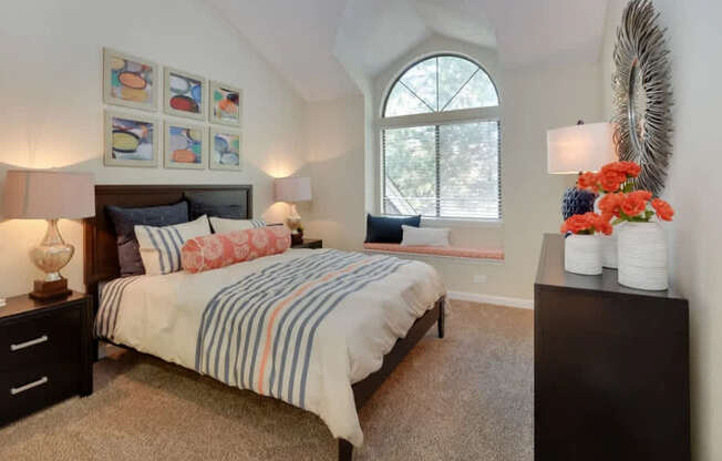 A bedroom with a bed, nightstand, and a window.