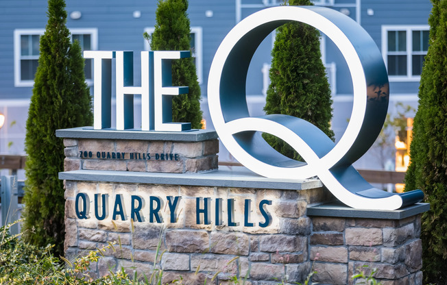 Outdoor sign on rough-finished brick pedestal for The Q | Quincy, Massachusetts Apartments