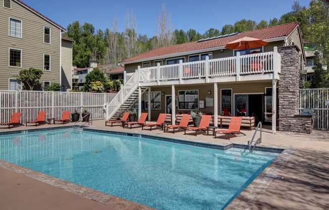 a swimming pool with orange chairs in front of resident clubhouse at 2000 Lake Washington Apartments, Renton, WA, 98056