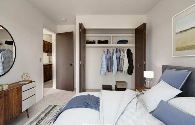 a bedroom with a large bed and a closet with clothes hanging on the wall