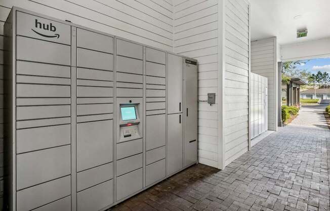 A row of Amazon hub vending machines are lined up on a brick walkway.