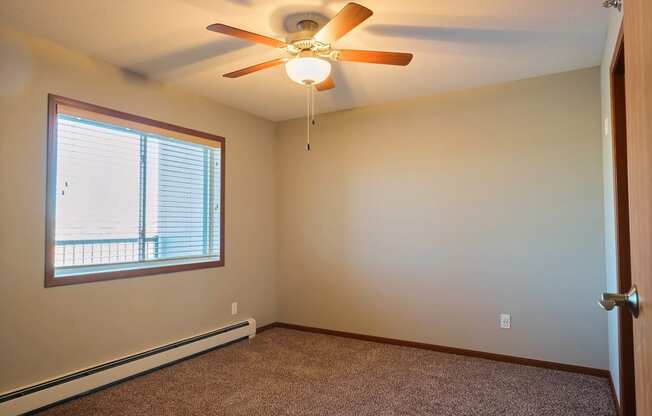 an empty bedroom with a ceiling fan and a window. Fargo, ND Urban Plains Apartments