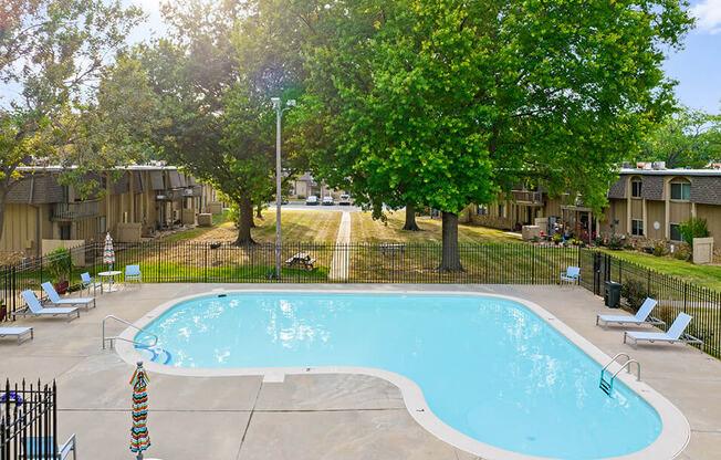 a swimming pool with chairs around it next to trees