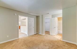 an empty living room with two open doors and a carpeted floor