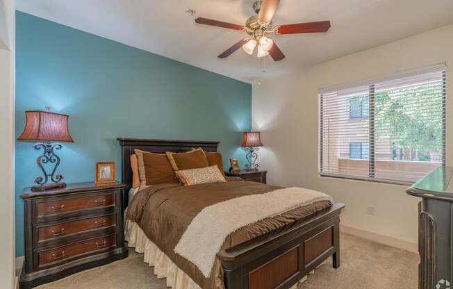 A bedroom with a bed, dresser, and ceiling fan.